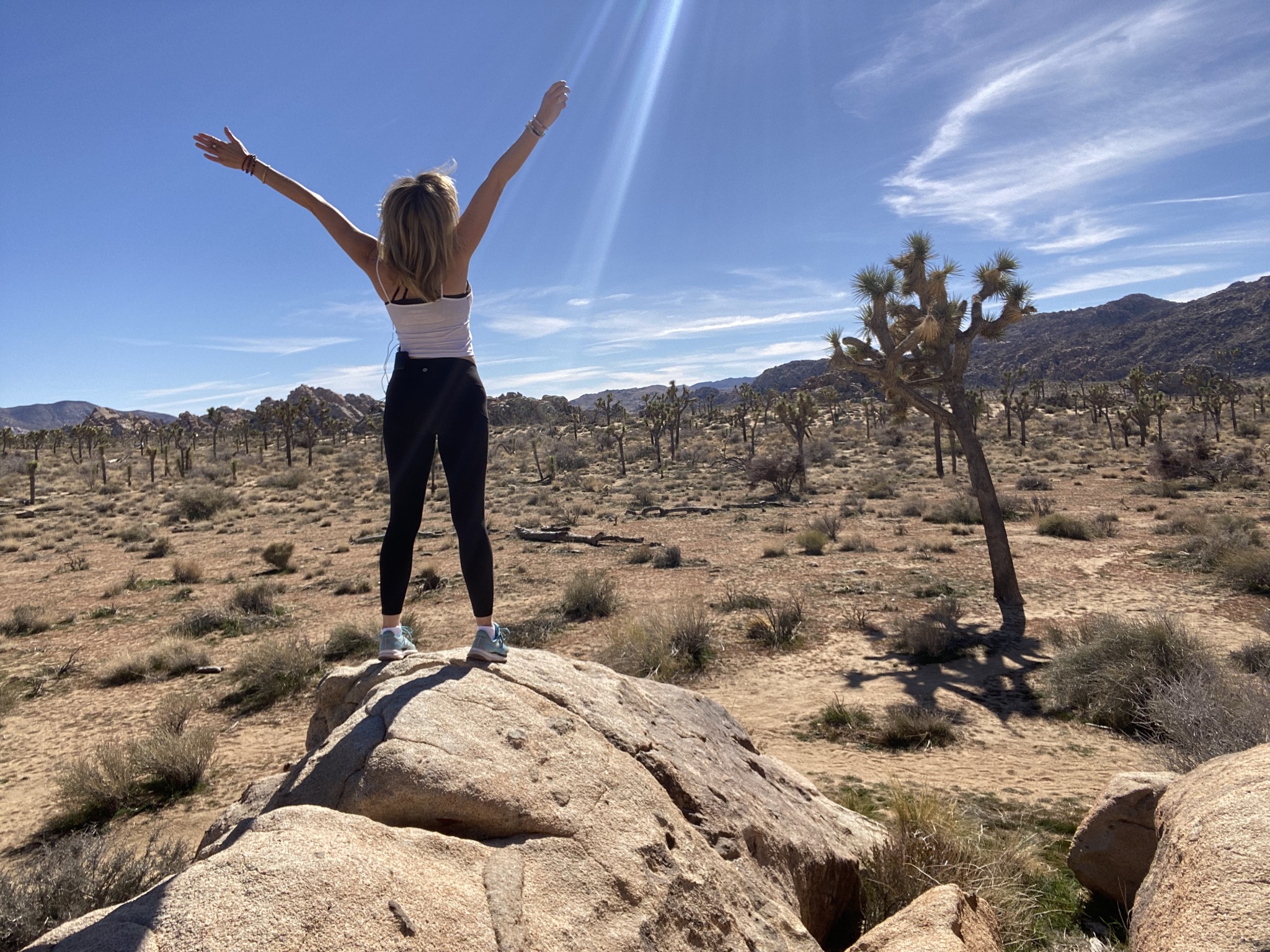 Lori Biesel in the desert with arms lifted